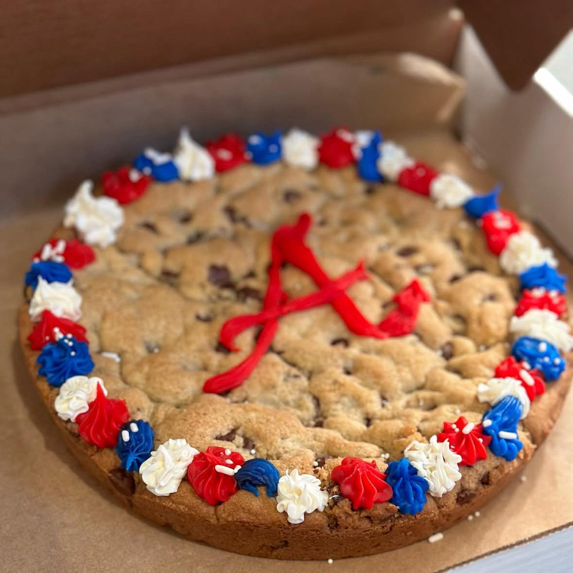 Cookie pizza with red, white, and blue decorations on a cardboard box.